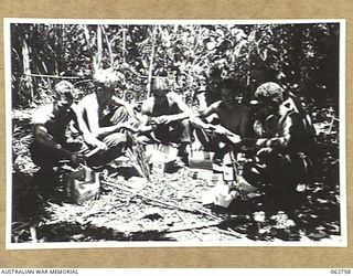 FINSCHHAFEN, NEW GUINEA. 1943-12-24. TRANSPORT DRIVERS OF HEADQUARTERS 9TH DIVISION EXAMINING THEIR AUSTRALIAN COMFORTS FUND CHRISTMAS HAMPERS