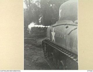 Personnel of the 754th United States Tank Battalion demonstrate a new type of flame thrower fitted to a General Sherman M4A1 medium tank to Australian and Allied officers at headquarters, 3rd ..