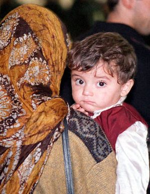 A Kurdish boy waits with his mother during immigration processing at Anderson Air Force Base, Guam, following an almost 17 hour flight from southern Turkey. Operation PACIFIC HAVEN represents a series of airlifts designed to provide sanctuary for some 2,700 refugees fleeing Iraq. Many are considered traitors by the Iraqi Government for working with the CIA-funded Iraqi National Congress and international humanitarian agencies. The Kurds will be housed at Andersen AFB, while they go through the immigration process for residence in the United States