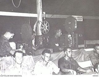 TOROKINA, BOUGAINVILLE, 1945-12-05. OPERATORS OF 1 DETACHMENT MOBILE CINEMA UNIT, MAKING ADJUSTMENTS TO THREE PROJECTORS USED FOR TESTING FILMS