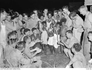 VIVIGANI, GOODENOUGH ISLAND, PAPUA NEW GUINEA. 1943-09-23. NATIVE CHILDREN SING FOR AIRMEN AT THE CAMP OF NO. 30 (BEAUFIGHTER) SQUADRON RAAF