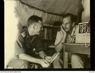 TOROKINA, BOUGAINVILLE ISLAND, SOLOMON ISLANDS. C. 1945-02. CONDUCTING INVESTIGATIONS INTO TROPICAL FATIGUE IN THE RAAF, MAJOR D. A. K. LEE OF BRISBANE, QLD (LEFT), CONFERS WITH RAAF MEDICAL ..