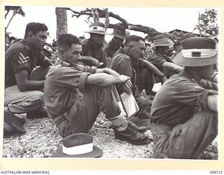 DALLMAN HARBOUR, NEW GUINEA. 1945-11-11. PERSONNEL OF C COMPANY, 2/5 INFANTRY BATTALION, SEATED ON THE GROUND LISTENING TO THE ADDRESS GIVEN BY CHAPLAIN W.B. HOWDEN, DURING A MEMORIAL SERVICE HELD ..