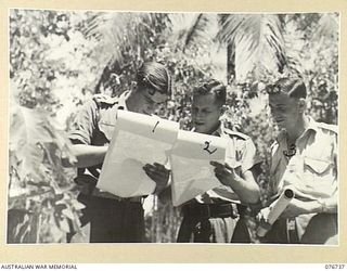 LAE, NEW GUINEA. 1944-11-09. NX90652 LIEUTENANT J.S. TALBOT, SURVEYOR (1) WARRANT OFFICER II, W. SPENCER, DRAUGHTSMAN (2) AND SERGEANT H.M. CROSSLEY (3) CHECKING MAPS OUTSIDE THE DRAWING OFFICE OF ..