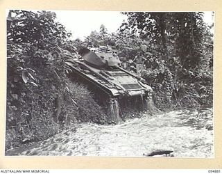 TOROKINA AREA, BOUGAINVILLE. 1945-08-08. AN M24 GENERAL CHAFFEE LIGHT TANK, IN A SECOND ATTEMPT, SUCCESSFULLY NEGOTIATING A THREE FOOT SIX INCH HIGH BANK DURING TRIALS CONDUCTED FOR THE WAR OFFICE