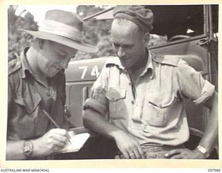 WEWAK AREA, NEW GUINEA. 1945-10-13. WARRANT OFFICER 2 W. DUNN (1) RECEIVING FROM SERGEANT T. NISBET (2) THE LIST OF TYRES COLLECTED BY MEMBERS OF 3 MOBILE TYRE WORKSHOP SECTION. THE TOTAL FOR THE ..