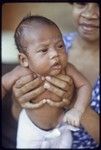 Proud mother holds up young infant wearing cloth diaper