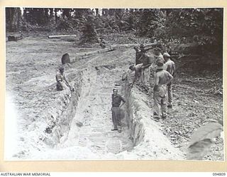 TOROKINA AREA, BOUGAINVILLE, 1945-08-08. TROOPS MEASURING THE WIDTH OF A DITCH EIGHT FEET WHICH AN M24 GENERAL CHAFFEE LIGHT TANK WILL ATTEMPT TO CROSS DURING TRIALS CONDUCTED FOR THE WAR OFFICE