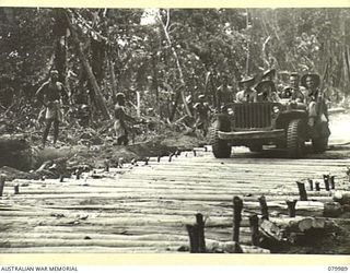 TOKO-BARARA ROAD, BOUGAINVILLE, SOLOMON ISLANDS. 1945-03-28. TROOPS OF THE 15TH FIELD COMPANY, ROYAL AUSTRALIAN ENGINEERS, CROSS A CORDUROY SECTION OF THE ROAD CONSTRUCTED BY NATIVES FROM THE ..