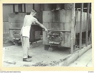 PORT MORESBY, NEW GUINEA. 1944-04-20. VX132408 CORPORAL W.A. WILSON, ATTACHED FROM THE 13TH FIELD BAKERY, FIRES OVENS AT THE 6TH FIELD BAKING PLATOON. IT IS THE RESPONSIBILITY OF THE STOKER TO ..