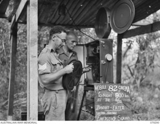 KALAI PLANTATION, HENRY REID BAY, NEW BRITAIN. 1945-02-17. NX173054 SERGEANT R.E. GEORGE (1) AND NX55910 SGT H. WINSTON (2) 82 MOBILE CINEMA, PREPARING THEIR PROJECTOR IN THE PLANTATION FOR THE ..