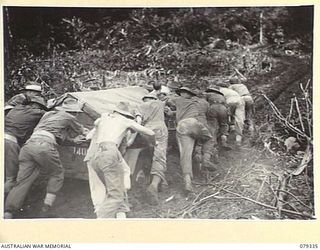 BOUGAINVILLE ISLAND. 1945-03-01. TROOPS OF THE 7TH INFANTRY BRIGADE PUSHING THE YOUNG MEN'S CHRISTIAN ASSOCIATION JEEP, CARRYING HOT TEA FOR THE FORWARD TROOPS, THROUGH A VERY MUDDY SECTION OF THE ..