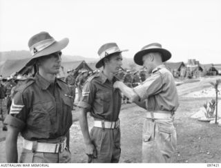 WEWAK POINT, NEW GUINEA. 1945-10-02. LIEUTENANT COLONEL R.R. GORDON, COMMANDING OFFICER 2/3 MACHINE-GUN BATTALION (3) PINNING THE MILITARY MEDAL RIBBON ON CORPORAL G.A. LAMBERT, A MEMBER OF 12 ..