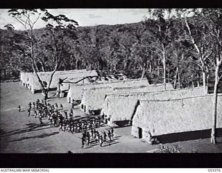 BISIATABU, SOGERI VALLEY, NEW GUINEA. 1943-07-01. "C" COMPANY, 1ST PAPUAN INFANTRY BATTALION BREAK OFF TO THEIR SLEEPING QUARTERS AFTER PARADE AT BASE DEPOT. HUTS ARE MADE OF KUNAI GRASS OVER ..