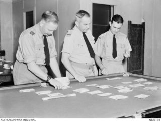 Probably Gulf of Carpentaria, Qld. 1943-08 to 1944-04? Flight Lieutenant R. J. McConnell of Rabaul, Flying Officer (FO) A. P. Muir of Brisbane, Qld and FO Burrow of New Guinea, looking for letters ..