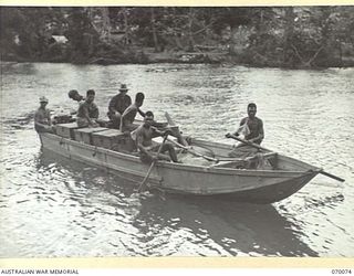 GOALING RIVER AREA, WEST NEW GUINEA. 1944-01-25. NATIVES PICTURED PADDLING TO THE SHORE OF THE GOALING RIVER IN AN ABANDONED JAPANESE BOAT WHICH HAS BEEN LOADED WITH JAPANESE MEDICAL EQUIPMENT ..