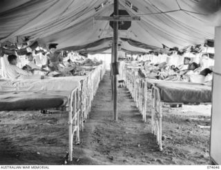 LAE. NEW GUINEA. 1944-07-14. WFX39558 SISTER C.E. FRICKER, AUSTRALIAN ARMY NURSING SERVICE TAKING THE TEMPERATURE OF A PATIENT IN ONE OF THE TENT WARDS OF THE 2/7TH AUSTRALIAN GENERAL HOSPITAL