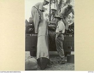 BOUGAINVILLE ISLAND. 1944-12-25. OFFICERS OF HEADQUARTERS, 3RD DIVISION AND THE RAAF PACKING A "AUSTER" AIRCRAFT PROPELLER INTO A "STOREPEDO" FOR DROPPING TO A NEW ZEALAND PILOT WHO HAS CRASH ..