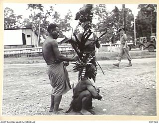 LAE, NEW GUINEA. 1945-09-07. CHIMBU CHIEFS AND AN AUSTRALIAN NEW GUINEA ADMINISTRATIVE UNIT NATIVE ATTENDANT ON ARRIVAL AT HEADQUARTERS FIRST ARMY. THE CHIEFS ARRIVED TO PAY THEIR RESPECTS TO THE ..