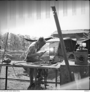 CAPE WOM, WEWAK AREA, NEW GUINEA. 1945-08-29. CORPORAL V. JESSUP WELDING AT 110 BRIGADE WORKSHOP, CORPS OF AUSTRALIAN ELECTRICAL AND MECHANICAL ENGINEERS