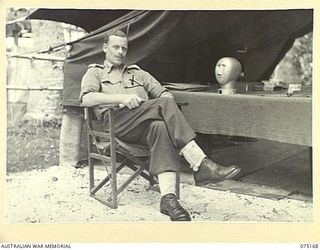 MILILAT, NEW GUINEA. 1944-08-09. VX20318 LIEUTENANT-COLONEL C.W.T. KYNGDON, ASSISTANT ADJUTANT AND QUARTERMASTER GENERAL 5TH DIVISION OUTSIDE HIS TENT. NOTE THE JAPANESE RESPIRATOR TESTER ON HIS ..