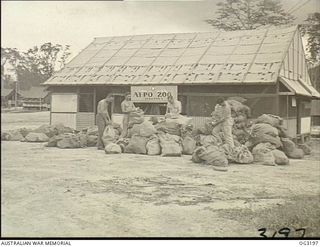 TOROKINA, BOUGAINVILLE ISLAND, SOLOMON ISLANDS. 1945-07-26. MAILBAGS PILED OUTSIDE THE RAAF AREA POST OFFICE WHEN A RECORD SHIPMENT OF TEN TONS OF SECOND CLASS MAIL MATTER ARRIVED ON 1945-07-24. ..