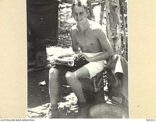 KILIGIA, NEW GUINEA. 1944-03-20. MR. PAUL BECKER OF THE AUSTRALIAN PUBLIC RELATIONS FIELD UNIT, USING HIS TYPEWRITER ON HIS LAP