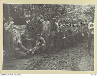 9 Infantry Battalion troops lining up at the YMCA tea stall at battalion headquarters on the Hatai Track. Identified in line are (left to right): V50654 Private (Pte) D A Wilksch, Vic; V501268 Pte ..