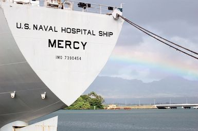 The U.S. Navy Military Sealift Command Mercy Class Hospital Ship USNS MERCY (T-AH 19) sits moored pier side moor at Naval Station Pearl Harbor, Hawaii, on Sept. 20, 2006, for a brief port visit enroute to its homeport at Naval Base San Diego, Calif., while in the background a rainbow is seen spanning the Ford Island Bridge. The MERCY, a converted San Clemente Class Super Tanker, is at the end of a five-month humanitarian and civic assistance deployment to Southern and Southeast Asia. (U.S. Navy photo by Mass Communication SPECIALIST 1ST Class James E. Foehl) (Released)