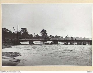 LAE AREA, NEW GUINEA, 1945-06-27. THE BUTIBUM BRIDGE OVER THE BUTIBUM RIVER, HEADQUARTERS FIRST ARMY AREA SHOWING RECEDING FLOODWATERS. THE RIVER OVERFLOWED ITS BANKS DURING RECENT HEAVY RAIN AND ..