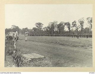 LAE, NEW GUINEA. 1944-09-29. VX13 LIEUTENANT GENERAL S.G. SAVIGE, CB, CBE, DSO, MC, ED, GOC NEW GUINEA FORCE TAKING THE GENERAL SALUTE FROM MEMBERS OF THE 6TH INFANTRY BRIGADE ON HIS ARRIVAL AT THE ..