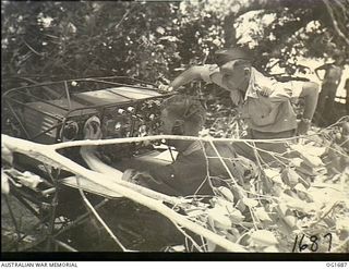 Aitape, North East New Guinea. C. 1944-12-25. Two members of a RAAF Signals Unit operating a transmitter unit in an area surrounded by trees not long after landing on the beach-head