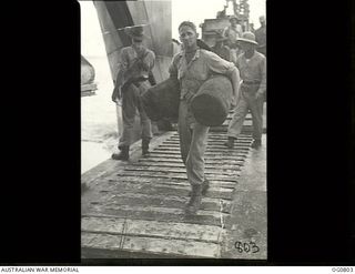MOMOTE, LOS NEGROS ISLAND, ADMIRALTY ISLANDS. 1944-03-18. CORPORAL J. H. RICHARDS CARRIES HIS KIT ASHORE FROM A LANDING CRAFT
