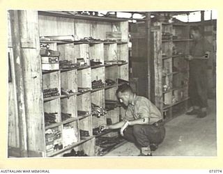 LAE, NEW GUINEA. 1944-06-09. NX116593 CORPORAL K. EDENBOROUGH (1), AND NX42080 CORPORAL K.A. CORNER (2), MEMBERS OF THE 2/7TH ADVANCED WORKSHOP CHECKING TOOLS IN THE TECHNICAL STORE. TOOLS ARE ..