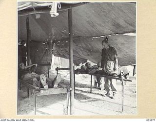 WIRUI BEACH, WEWAK AREA, NEW GUINEA. 1945-08-31. THE RECEIVING TEND FOR PATIENTS, 2/1 FIELD AMBULANCE. PRIVATE J.S. SULLIVAN (1), ON STRETCHER ATTENDED BY PRIVATE R.E. NEICH (2) AND PRIVATE P.V. ..