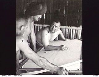 YULE ISLAND, NEW GUINEA, 1944-11TH TO 20TH MAY. VX90586 LIEUTENANT W.R. BURGESS, OFFICER-IN-CHARGE, 1ST MARINE FOOD SUPPLY PLATOON (1), DISCUSSION WITH HIS MEN THE PLANS FOR A DIESEL DRIVEN 90 FOOT ..