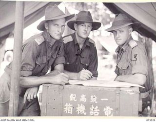 HANSA BAY, NEW GUINEA. 1944-09-07. OFFICERS OF B COMPANY, 25TH INFANTRY BATTALION CHECKING PATROL REPORTS AT THEIR CAMP HEADQUARTERS ON THE BOROI RIVER. IDENTIFIED PERSONNEL ARE:- QX37528 ..