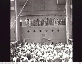 AT SEA, EN ROUTE TO MOROTAI, 15 APRIL 1945. MEMBERS OF 2/9 ARMOURED REGIMENT ATTENDING CHURCH PARADE ON NO 3 HATCH ABOARD THE UNITED STATES ARMY TRANSPORT, SS SEABARB. IN BACKGROUND CAN BE SEEN THE ..