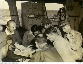 Colonel R.W. Savige, Chief Staff Officer (right), attending a conference with Australian and Japanese staff officers after the surrender ceremony aboard the aircraft carrier HMS Glory. The ..