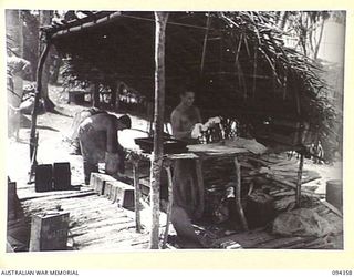 ULUNKOHOITU, NEW GUINEA, 1945-07-18. PTE J.E. KELLY (1) AND PTE C.M. BARNIER (2), COOKS OF 7 PLATOON, A COMPANY, 2/6 INFANTRY BATTALION, PREPARING FOOD. PTE BARNIER IS ROLLING THE DOUGH FOR BUN ..