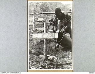 KUMBARUM, NEW GUINEA, 1943-10-23. A NATIVE WATERING A FRESHLY PLANTED SHRUB NEAR GRAVES IN THE WAR CEMETERY AT HEADQUARTERS, 7TH AUSTRALIAN DIVISION AREA
