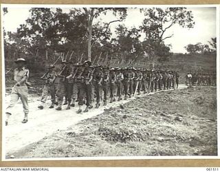 POM POM VALLEY, NEW GUINEA. 1943-11-30. 2/12TH AUSTRALIAN INFANTRY BATTALION, ADVANCING IN "COLUMN OF ROUTE" AS THEY MARCH OFF THE SPORTSGROUND. QX34584 LIEUTENANT C. W. BARR (1); PRIVATE W. ..