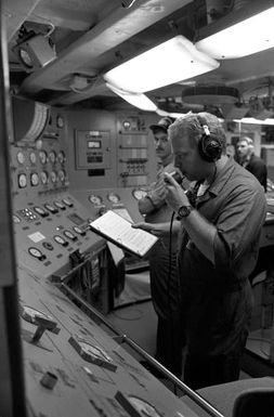 A sailor in an engineering space aboard the amphibious assault ship USS SAIPAN (LHA 2) consults a manual while preparing to make an adjustment to the ship's No. 1 boiler. The SAIPAN is on station off the coast of Liberia for Operation Sharp Edge