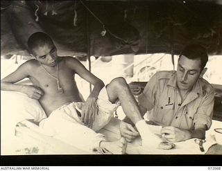 Heldsbach, Finschhafen Area, New Guinea. 1944-04-06. V211859 Private W.H. Richardson of the 106th Australian Casualty Clearing Station treating the foot of a Japanese prisoner of war