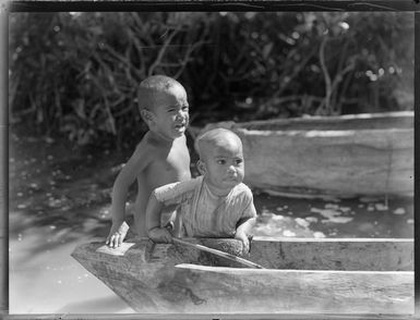 Tongan children, playing at the water's edge, with a canoe