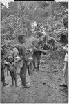 Pig festival, singsing preparations: men with kundu drums beside cordyline plants at men's house