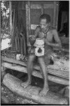 Carving: M'lapokala carving a wooden bowl with a stand, probably for tourist trade, other carvings (l)