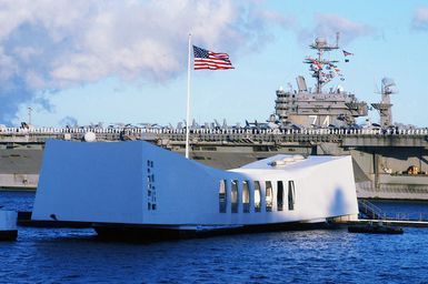 The US Navy (USN) Nimitz Class Aircraft Carrier USS JOHN C. STENNIS (CVN 74) passes the battleship USS ARIZONA (BB 39) memorial as it arrives at Pearl Harbor. The STENNIS and Carrier Air Wing 14 (CVW 14) are taking part in Exercise Rim of the Pacific (RIMPAC) 2004. RIMPAC is the largest international maritime exercise in the waters around the Hawaiian Islands. This years exercise includes seven participating nations: Australia, Canada, Chile, Japan, South Korea, the United Kingdom and the United States. RIMPAC is intended to enhance the tactical proficiency of participating units in a wide array of combined operations at sea, while enhancing stability in the Pacific Rim region