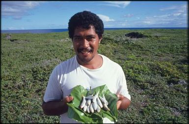 Man holding large leaf covered in small fish