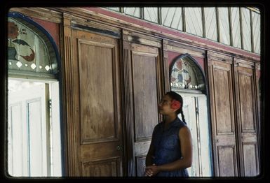 Manukura Marsters inside the Church of Zion, Palmerston Islet, showing panelling constructed from ship's pantry door